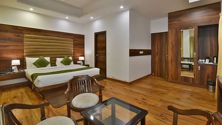 A large bed placed in front of two sofas at the Luxury Room Without Balcony at DLS Highland Resort and Spa, Mussoorie.